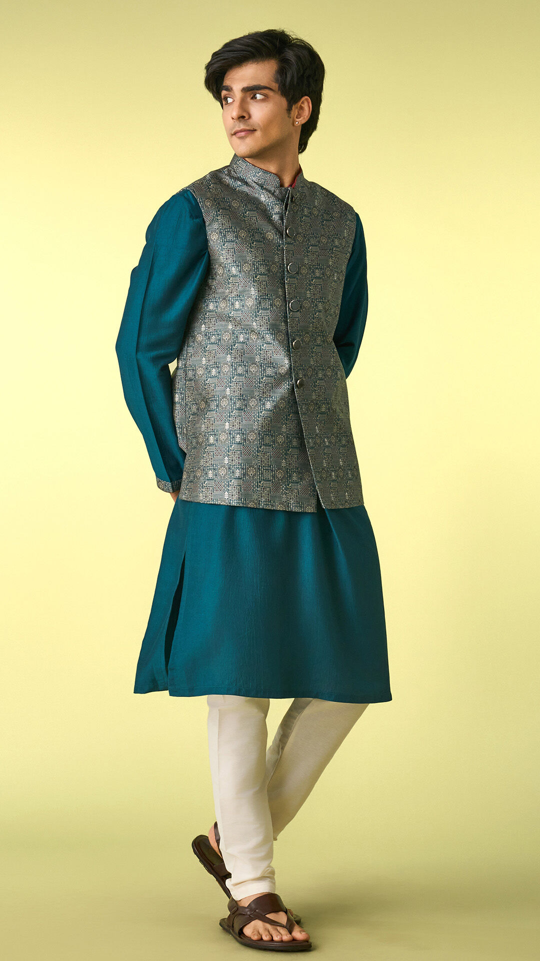 Man wearing a teal kurta with a patterned Nehru jacket, showcasing a refined ethnic look with contemporary festive styling.